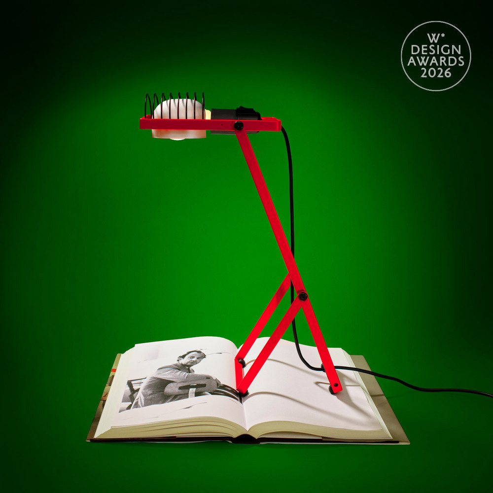 Red Sintesi lamp placed over an open catalog showing a black-and-white photo of Ernesto Gismondi, photographed by Pierpaolo Ferrari, against a green background featuring the Wallpaper* Design Awards logo.