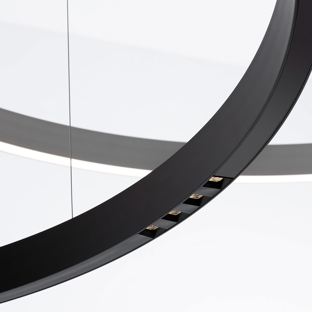 Gros plan d'une suspension circulaire noire avec spots LED intégrés orientés vers le bas sur le bord intérieur de l'anneau.