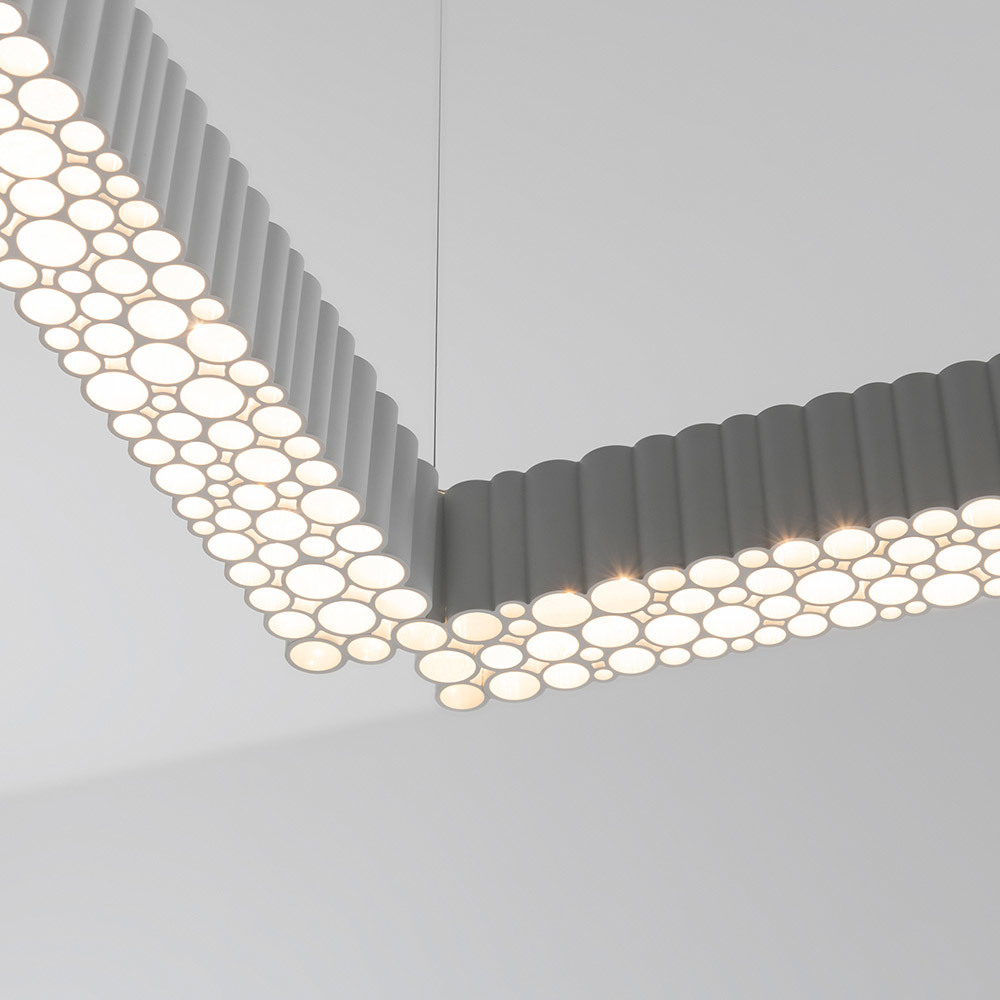 Gros plan d'un luminaire suspendu angulaire gris avec tubes cylindriques et diffuseurs LED circulaires formant un motif en nid d'abeille