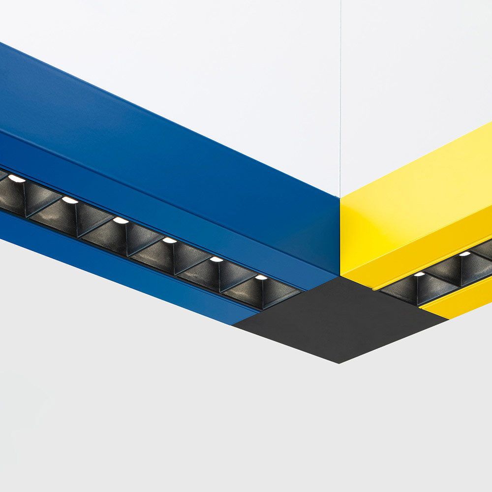 Système d'éclairage suspendu modulaire Artemide avec profilés en aluminium bleu et jaune se rejoignant en angle, avec modules LED noirs encastrés.