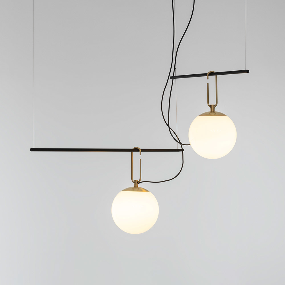 Suspension Artemide NH : deux sphères en verre opalin sur crochets en laiton accrochées à une barre horizontale noire, suspendue par des câbles noirs.