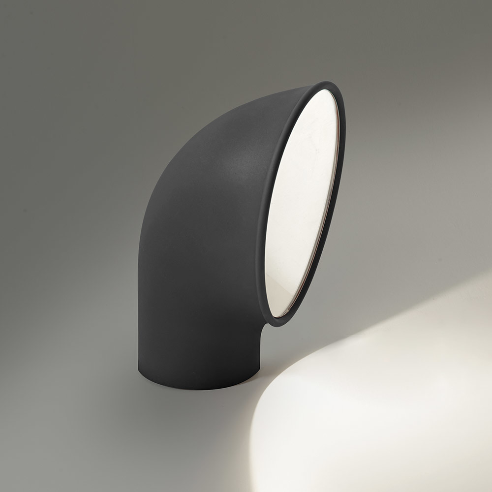 Lampe de sol Artemide en tube courbé gris foncé avec diffuseur circulaire incliné émettant une lumière directionnelle chaude vers le bas