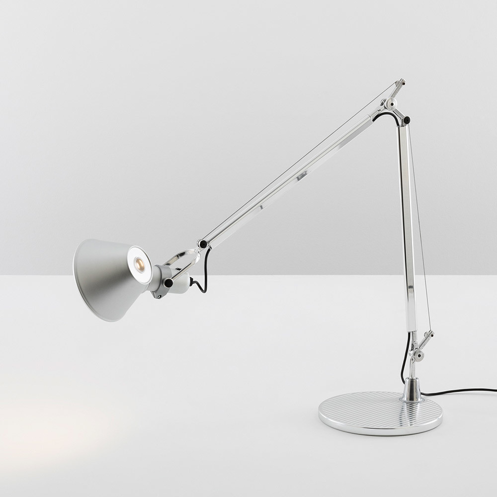 Lampe de bureau Artemide Tolomeo en aluminium poli avec bras articulé réglable, abat-jour conique et base circulaire sur surface blanche