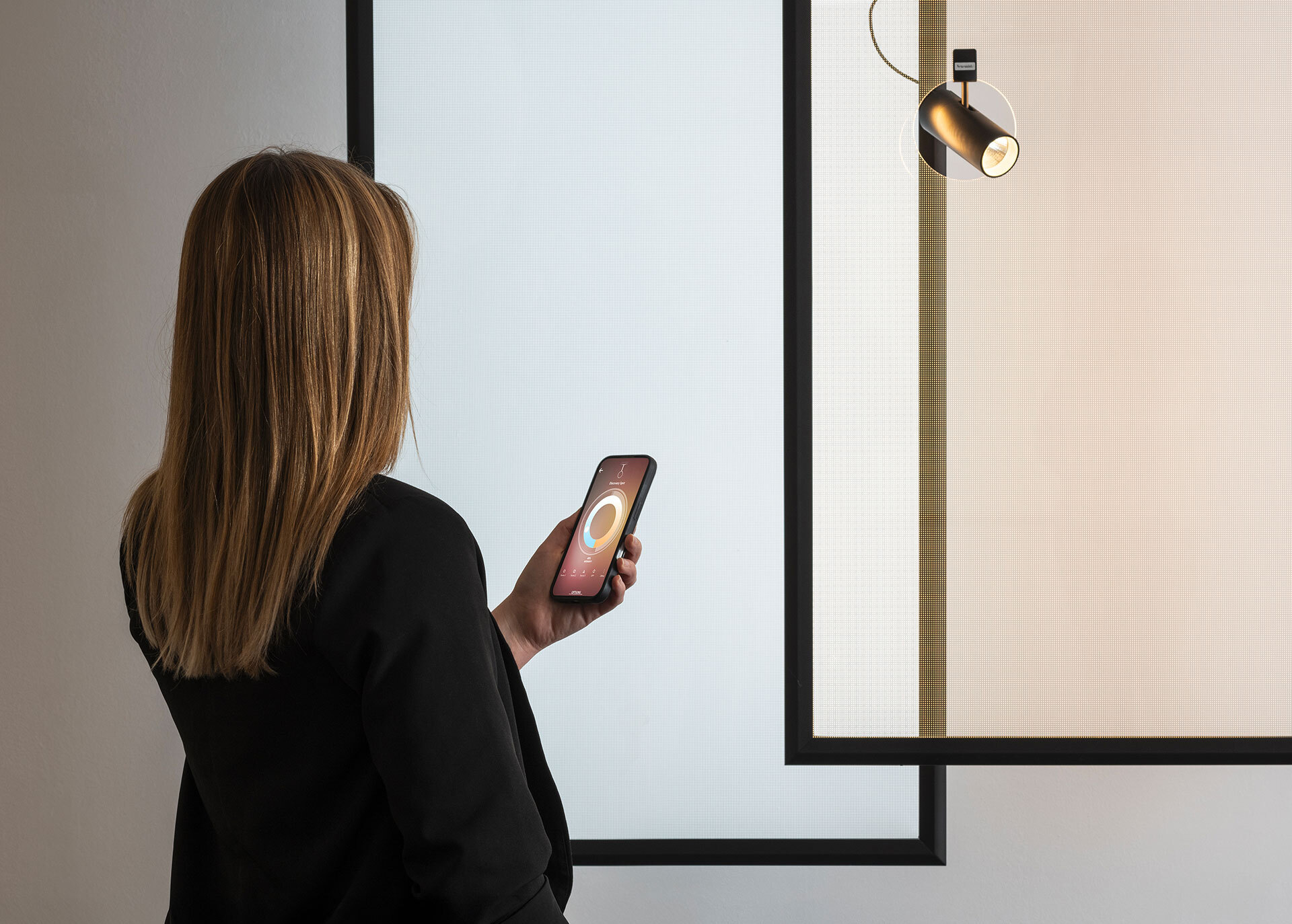 Woman adjusts a spotlight through a smartphone app.