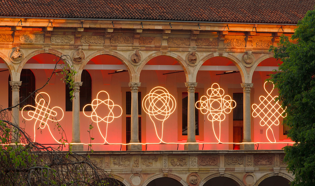 Front view of the portico of the University of Milan with a continuous light installation running across the arches.