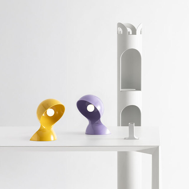 Composition on a white table with two Dalù lamps in lilac and yellow, set against a light background.