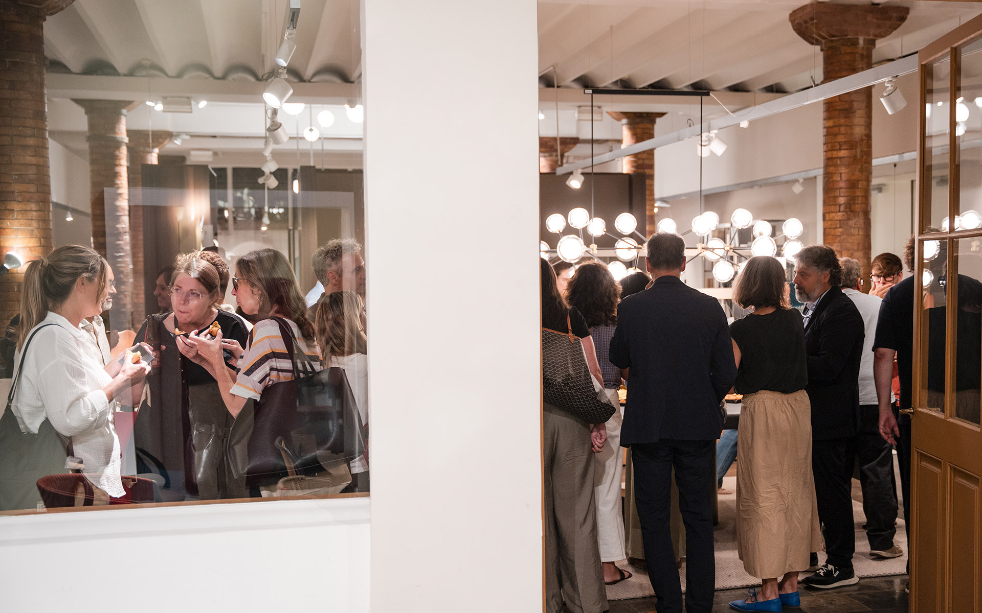 Guests gather at an Artemide lighting event, with spherical globe pendant lamps illuminating the elegant interior space.