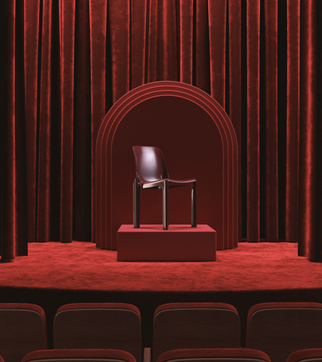 Bordeaux Selene chair displayed on a plinth in a theatrical setting with an arch and curtains.
