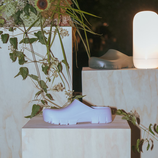 Colorful rubber sandals on wooden pedestals, illuminated inside a botanical garden