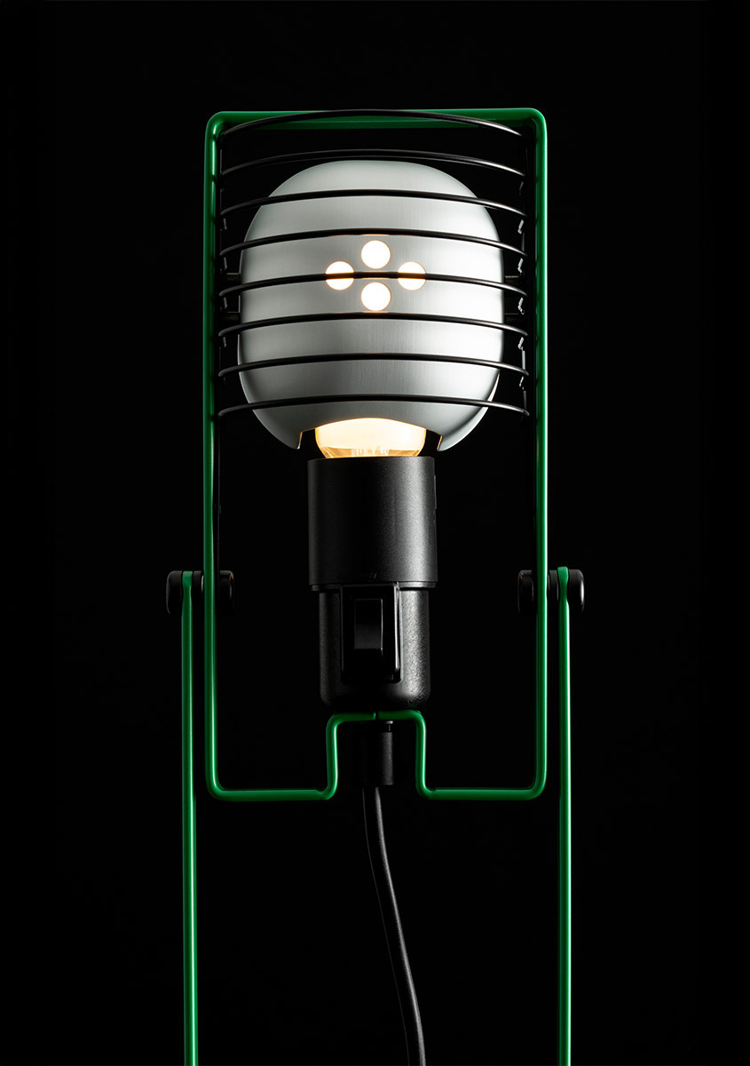 Close-up of the upper section of a green Sintesi lamp against a black background.