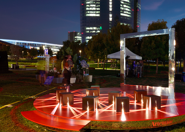 Light installation with cubes and red beams in an urban park at night.