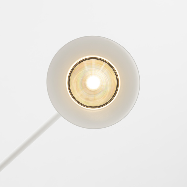 Primer plano de un cabezal de lámpara circular blanco visto desde arriba, con bombilla LED central, reflector iridiscente y luz cálida