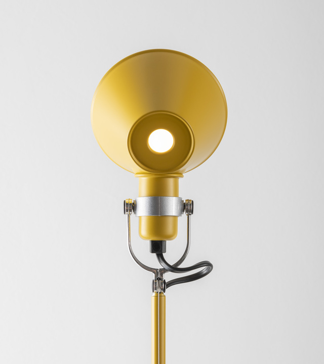 Close-up of the Tolomeo lamp diffuser in yellow painted aluminum, featuring an adjustable metal joint and illuminated against a light background.