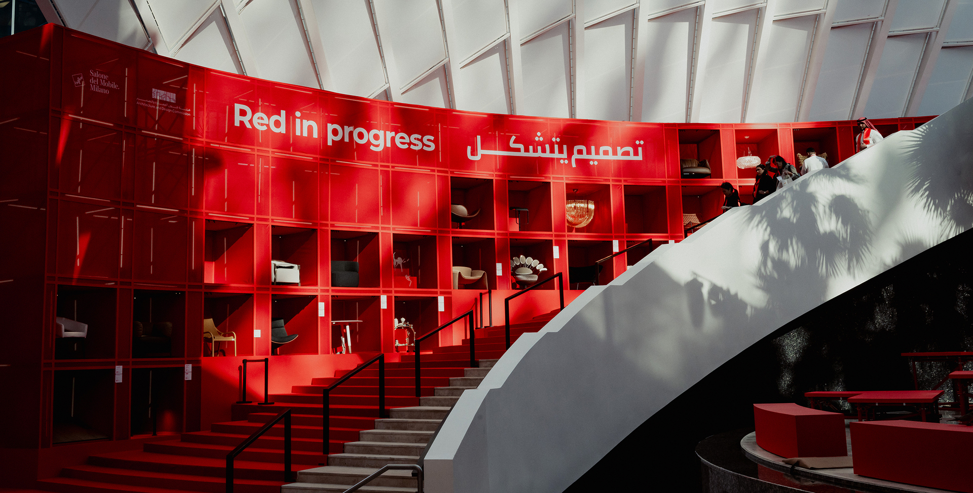 Render of the installation for Salone del Mobile.Milano in Riyadh: a red cell-like structure displaying the products, accompanied by a red staircase that follows its profile.