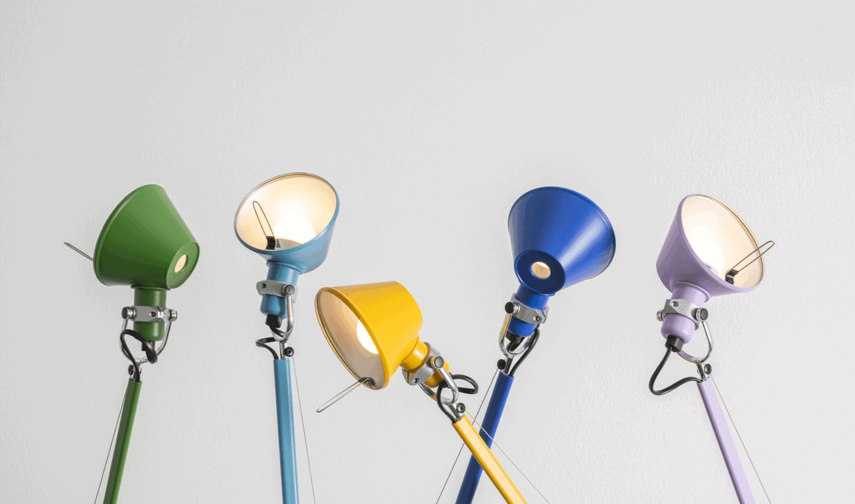 Collection of Tolomeo lamps with colorful diffusers and articulated painted aluminum arms against a neutral background.