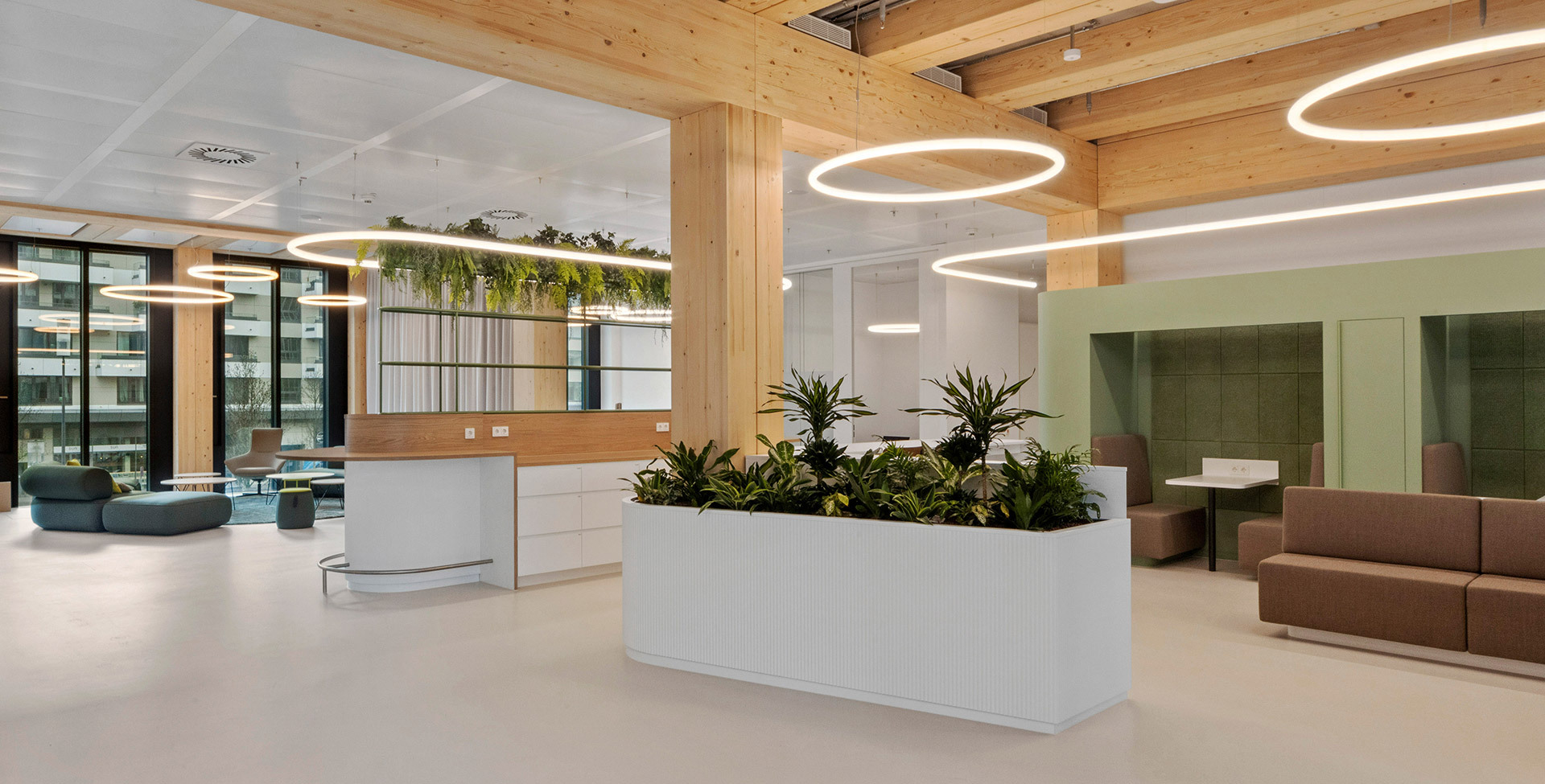 Open space with planters, lounge areas and circular lighting systems suspended in a timber structure.