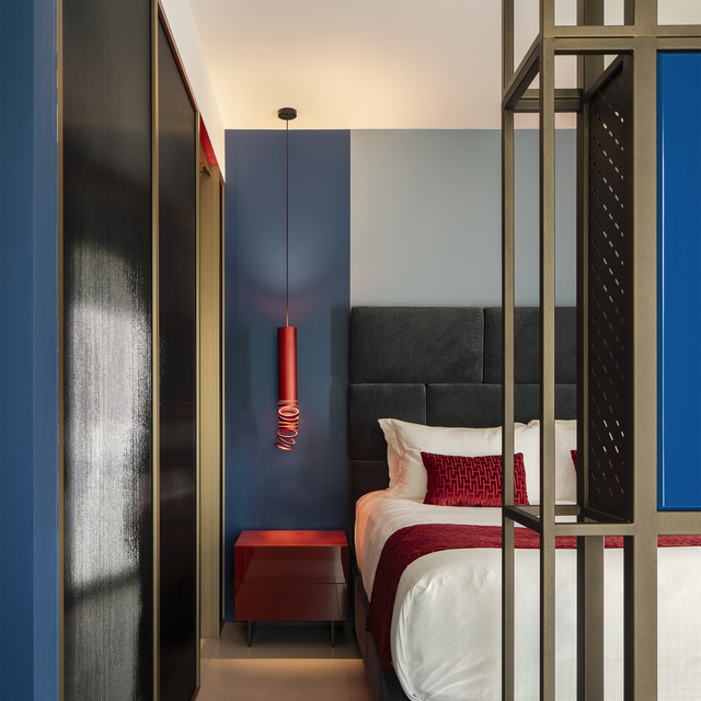 Image of the bedside table next to the bed, illuminated by a Decomposé suspension light.