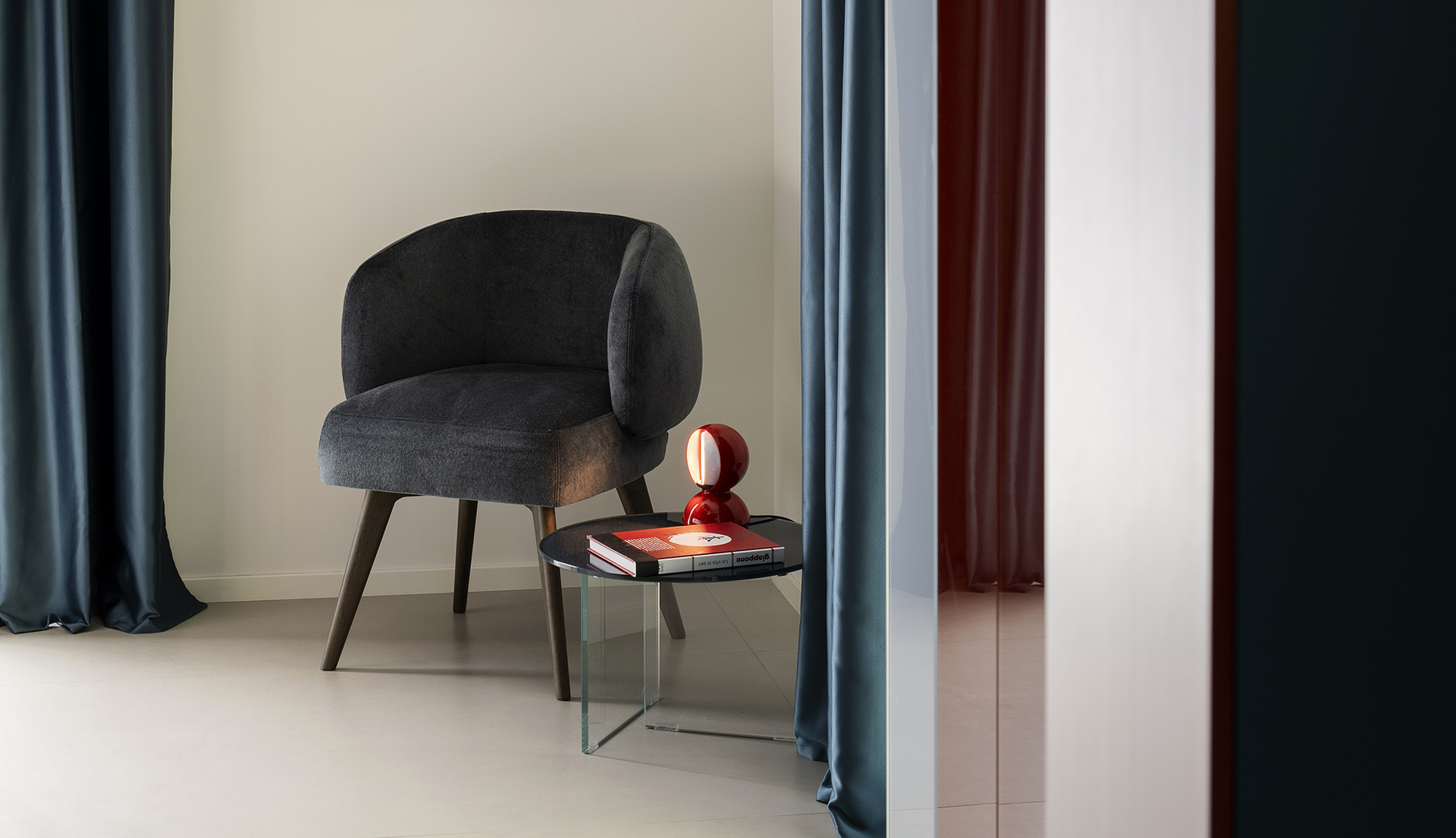 Image of the Eclisse lamp placed on a small table next to an armchair.